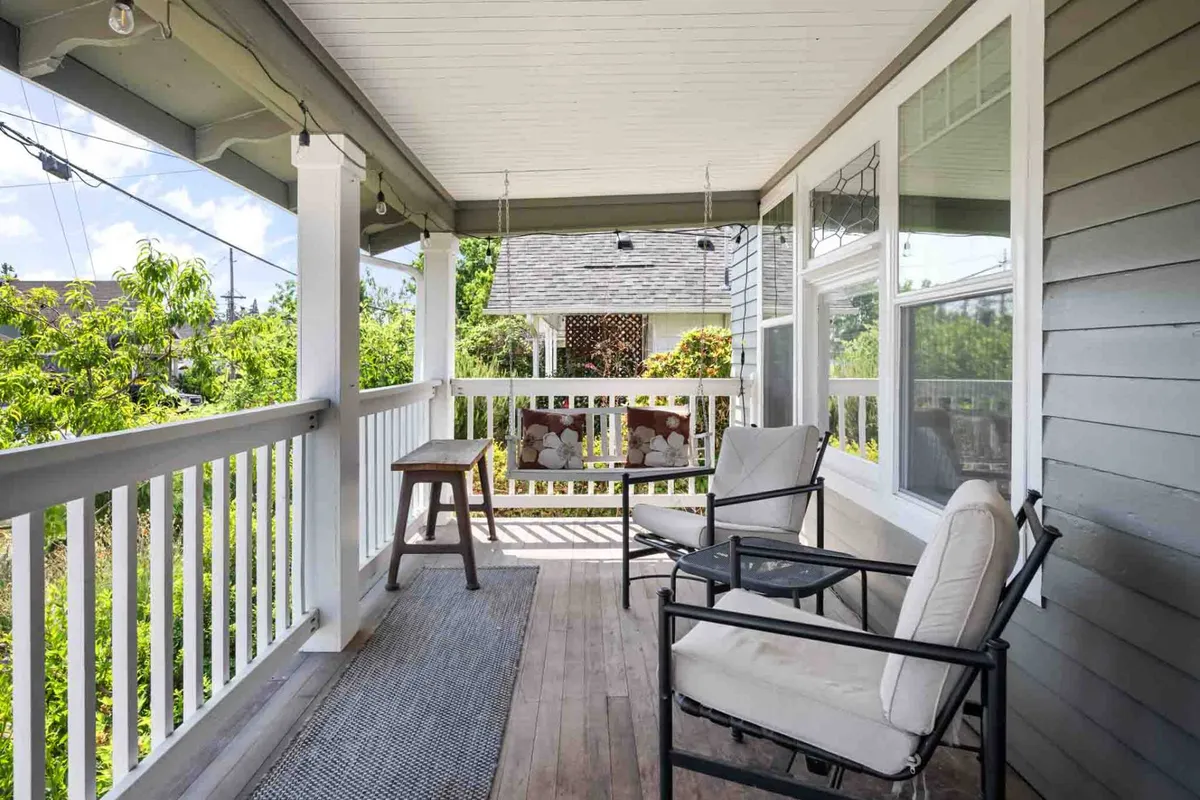 A charming front porch with rocking chairs, a wooden table, and decorative pillows, ideal for relaxing and enjoying the outdoors.