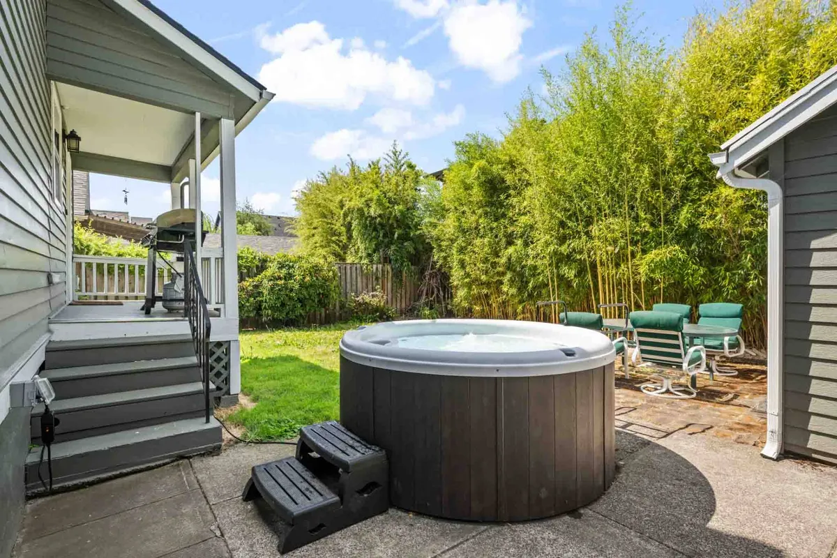 This image highlights the backyard area, featuring a bubbling hot tub, patio seating, and abundant greenery. The tranquil outdoor setting offers a space for socializing, relaxing, and sharing memorable experiences under the stars.