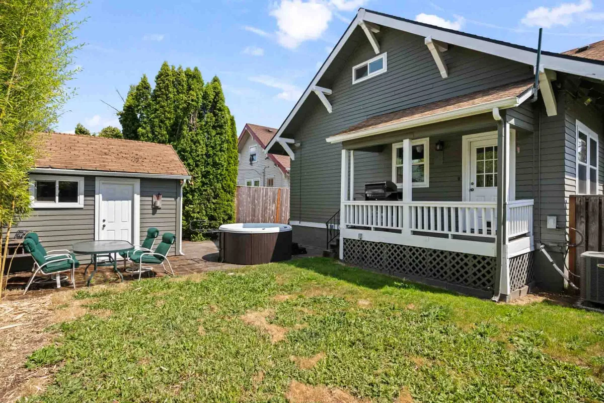 This exterior image showcases the fenced backyard with a relaxing hot tub, patio furniture, shed, and lush landscaping, providing a comprehensive view of the main outdoor living area. The space feels open yet private, with ample room for both relaxation and play, making it ideal for families and pet owners.