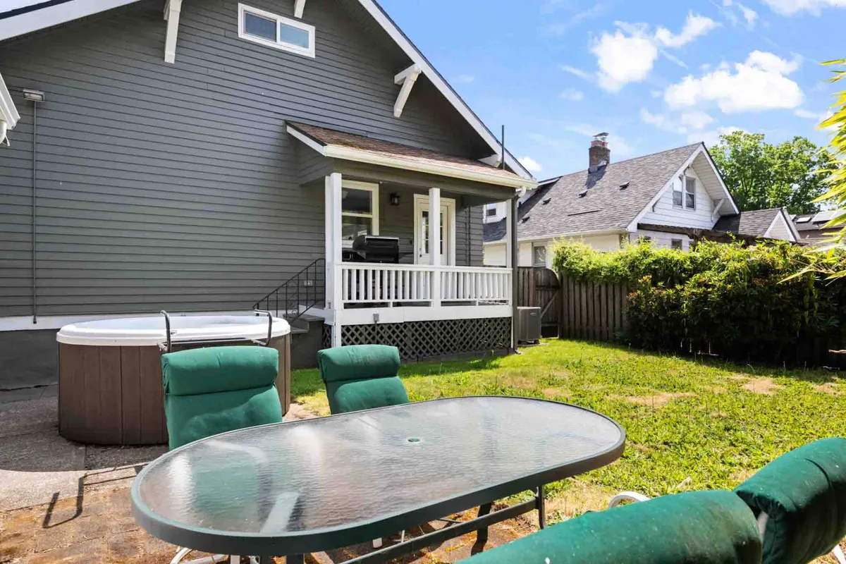This exterior image features a private hot tub on a back porch, complemented by a dining table and surrounded by a relaxed, inviting atmosphere. The scene suggests opportunities for outdoor relaxation, stargazing, and social gatherings in a tranquil setting.
