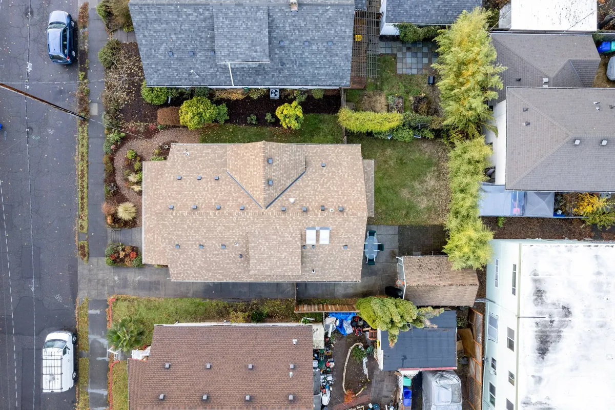 An aerial view of the property’s rooftops, landscaped gardens, and driveways. The peaceful neighborhood setting is visible, suggesting opportunities for neighborhood walks and backyard play.